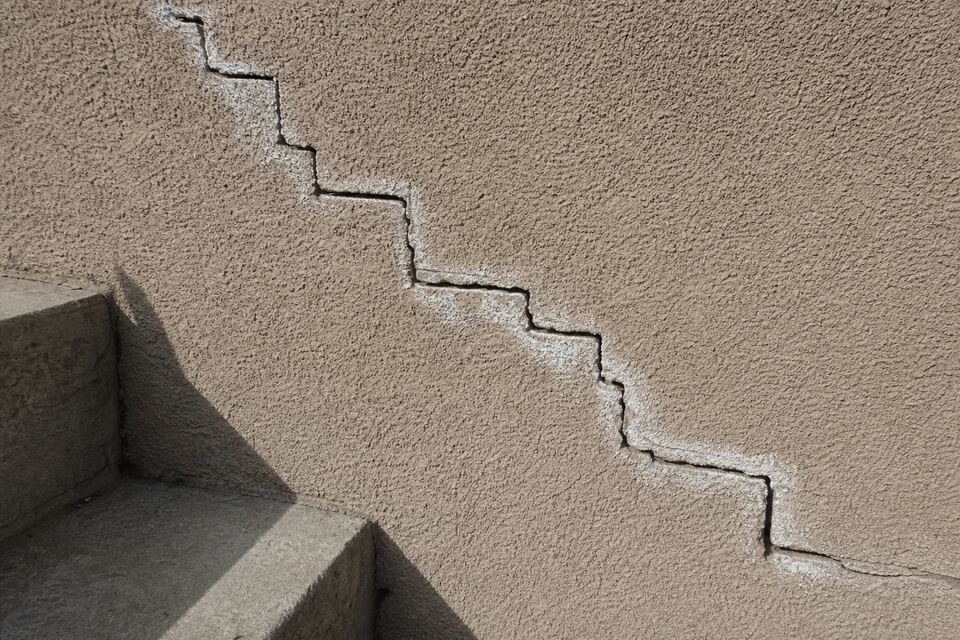 Close-up of a stair-step crack in tan stucco on a Santa Fe wall
